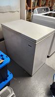Front left view of white chest freezer showing lid and plain front
