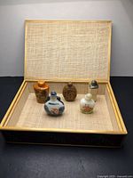 Open woven box displaying five snuff bottles