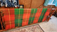 Full view of plaid wool blanket draped over banister showing color pattern and fringe