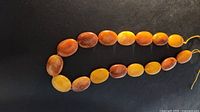 Entire strand of oval honey/butterscotch beads on black background