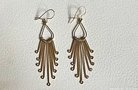 Full view of both fringe earrings laid flat on white surface