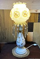 Lamp illuminated showing frosted shade, prisms, base