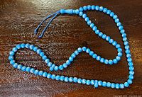 Full view of blue rosary laid out showing all beads and tassel