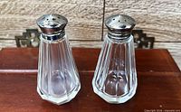 Front view of both crystal shakers showing faceted octagon bodies and silver-plated caps