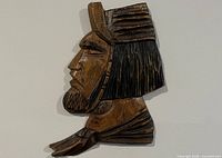 Full view of carved wooden head sculpture mounted on wall