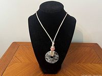 Full view of necklace displayed on bust showing pendant and cord