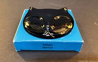 Front view of black cat-face mirror resting on blue box