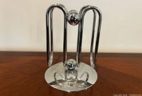 Front angle of chrome napkin/letter holder on wooden surface