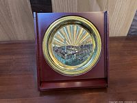 Front view of gold-tone plate on folding wooden stand