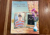 Box showing product image and labeling 'Photo Frame With Clock'