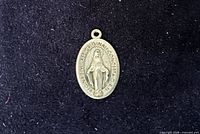 Front of pendant showing Virgin Mary and inscription