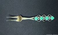 Front view of sterling two-tine fork showing green enamel handle detailing