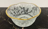 Clear art crystal bowl on black surface, showing relief detail and gold rim