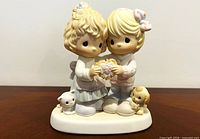 Front view of Precious Moments figurine showing two children holding heart and pets at base