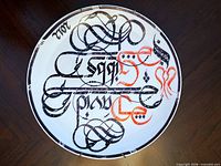 Front view of porcelain plate showing full calligraphic design and attached brass hanger