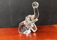 Front left view of clear crystal elephant figurine showing raised trunk and facets