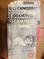 Front view stack showing Swimming, Camping, Cooking, Canoeing, Lifesaving pamphlets