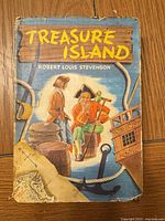 Front cover of Treasure Island showing title, author, illustration, edge wear