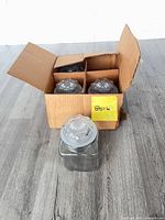 Cardboard box containing four glass jars, one jar displayed in front