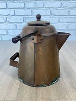 Side view showing full copper coffee pot, lid, spout, side bracket