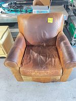 Front view of brown leather armchair showing overall design and heavy wear