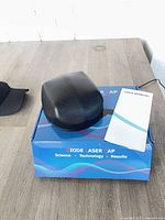 Laser cap in carrying case on retail box with baseball cap visible