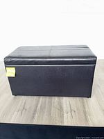 Front view of black faux leather storage ottoman