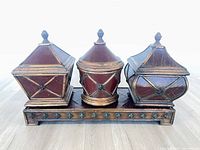 Front view of three lidded boxes on stand showing overall design