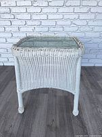 Overall view of white plastic wicker end table showing glass top