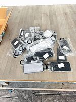 Pile of 35 individually bagged black phone cases with finger loops on tabletop