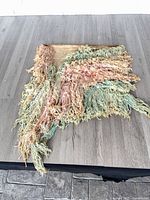 Full view of woven tapestry showing shape, colors and shag texture