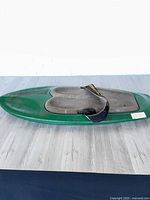 Full view of green kneeboard top side showing knee wells and strap