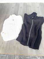 White and black ribbed sweaters laid flat
