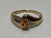 Top view of gold ring with oval orange gemstone and accent stones