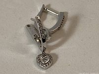 Front view of white gold earrings showing heart drops and stones