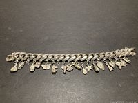 Full view of sterling silver charm bracelet showing curb links and attached charms