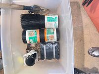 Clear tote with two rolls black plastic garden mesh, seed tray, shovel head visible, white pot