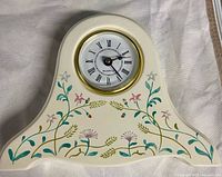 Front view of Russ porcelain mantle clock showing dial and hand painted floral design