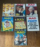 Six Mad magazines laid out showing cover art and issue numbers