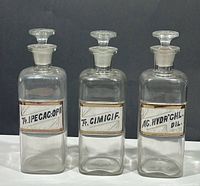 Front view of all three apothecary bottles with stoppers and labels visible
