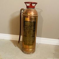 Front view of copper Imperial fire extinguisher showing red handle, hose, and full body