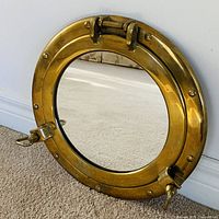 Front view of brass porthole mirror leaning on wall