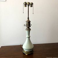 Full view of celadon porcelain lamp on table showing overall form and twin sockets