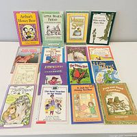 All 16 books laid out, four pictured upright, twelve flat