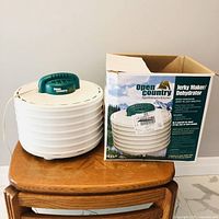 Dehydrator with stacked trays and green lid beside box