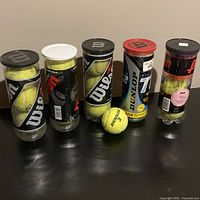 Five tennis ball cans and one loose ball on tabletop