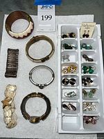 Overall view of seven bracelets and tray of assorted earrings