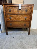 Front view of tiger oak dresser showing drawers and hardware