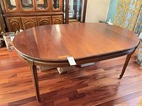 Top view of oval wood dining table with one leaf inserted