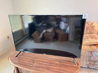 Front view of Westinghouse 50-inch Roku TV on wooden table with two feet stands